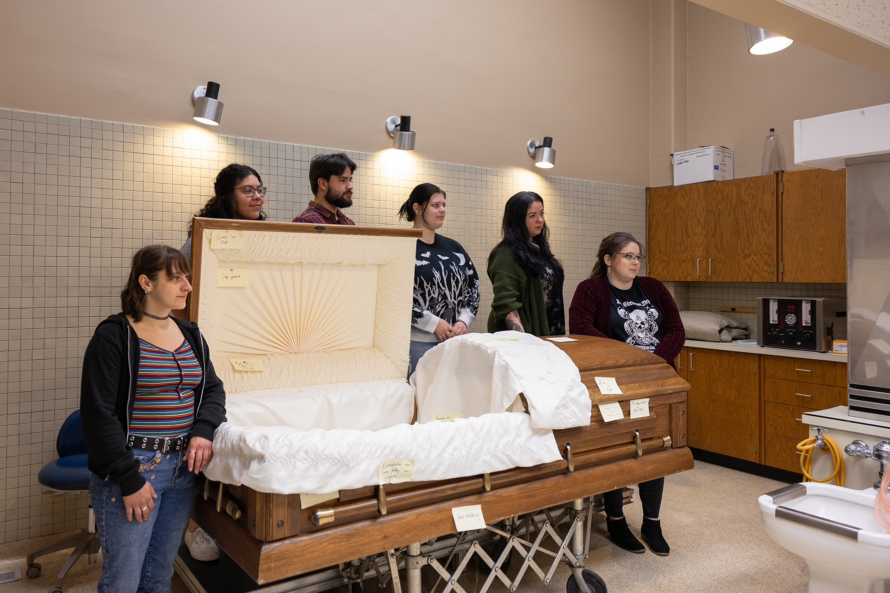 funeral services students standing around a casket